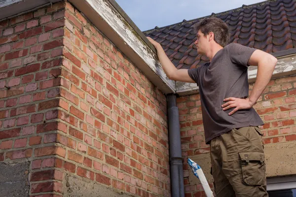 Jonge man inspectie van het dak van een oud huis Stockafbeelding