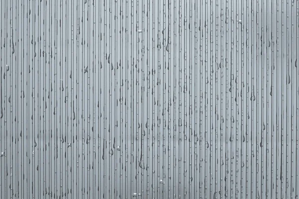 Gümüş rengi bir oluklu plaka üzerinde su damlaları — Stok fotoğraf
