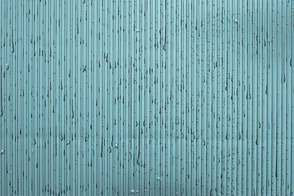 Vatten droppar på en korrugerad plåt av indigo färg — Stockfoto