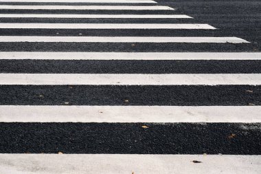 Siyah asfalt üzerinde beyaz çizgili yaya geçidi işaretleri