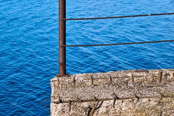 Eski bir beton ve metal yapı veya mavi suyun arka planına karşı çit