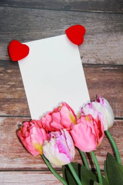 Pembe laleler, kırmızı kalp ve beyaz kart.