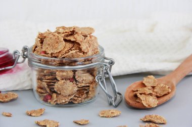 Cam kavanozda ve tahta kaşıkta kuru müsli.