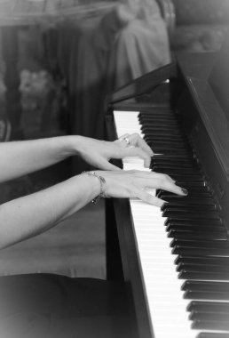 female hands play music on white and black piano keys