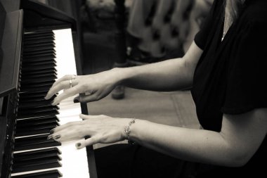 female hands play music on white and black piano keys