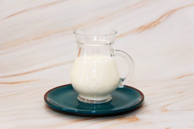 fermented milk drink ayran in a transparent decorative mug on a blue ceramic plate
