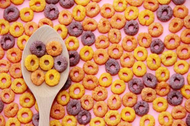 dry children's breakfast multicolored wheat rings in a wooden spoon