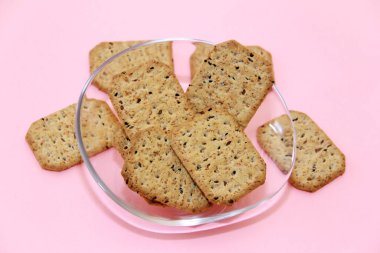 Dekoratif cam tabakta siyah kimyon ve kinoa içeren kuru kare diyet krakerleri.