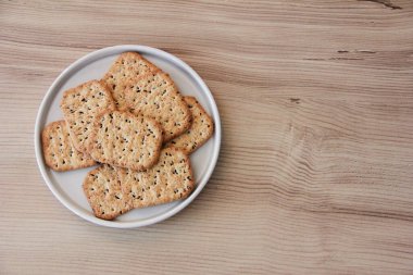 Kare tuzlu diyet krakerleri, siyah kimyon tohumları ve cam bir tabakta kinoa.