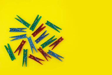 Çamaşırları bağlamak için kullanılan plastik mandallar sarı arka planda yıkanmış.