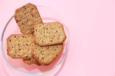 Kare krakerler, siyah kimyon tohumları ve cam bir tabakta kinoa.