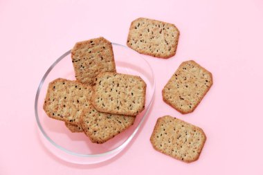 Kare krakerler, siyah kimyon tohumları ve cam bir tabakta kinoa.