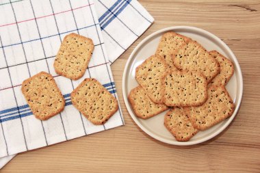 Kare krakerler, siyah kimyon tohumları ve cam bir tabakta kinoa.