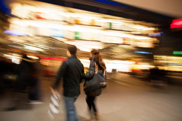 Couple with shopping bags walking past at dusk — Stock Photo, Image