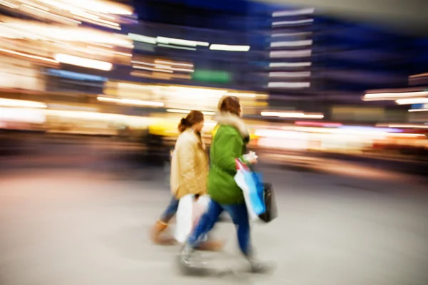 Två unga kvinnor shopping i staden i skymningen — Stockfoto