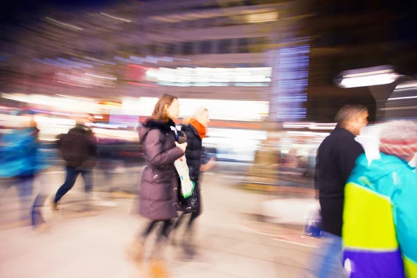 夕暮れ時に店の窓の前を歩いて買い物客 — ストック写真