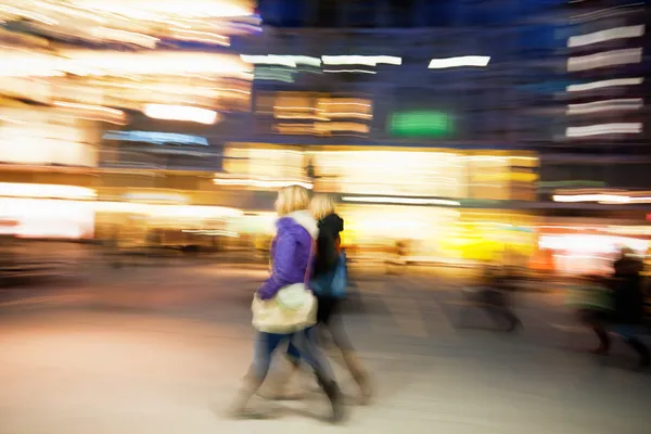 Junge Frauen laufen in der Abenddämmerung am Geschäft vorbei — Stockfoto