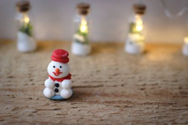 Noel dekoru. Minyatür bir pudra şekerli kardan adam kırmızı şapkalı tahta üzerinde duruyor..