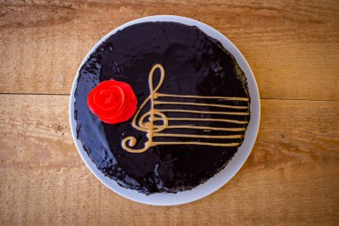 Kırmızı gül ve müzik personeli olan çikolatalı pasta.