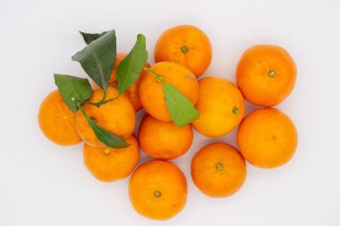 Beyaz arka planda yeşil yapraklı birkaç olgun mandalina.
