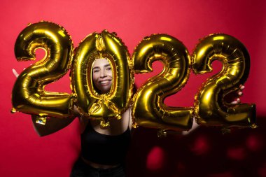 Siyah elbiseli neşeli genç bir kadın 2022 rakamlarını taşıyor.