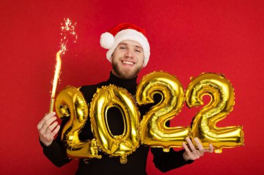Noel Baba şapkalı bir adam 2022 rakamlarını ve maytap taşır.