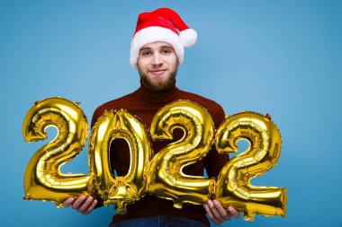 Kırmızı şapkalı bir adam 2022 yılının rakamlarını taşıyor.