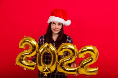 Noel, mutlu bayram kavramı - pijamalı genç bir kadın ve Noel Baba şapkası 2022 rakamlarını barındırıyor.