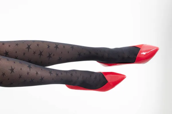 パターン化されたタイツと赤のハイヒールで女性の足のクローズアップ — ストック写真