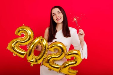 Noel Tatili Konseri - Beyaz elbiseli genç bir kadın üzerinde 2022 rakamları ve maytap taşıyor