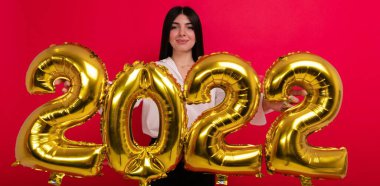 Yaklaşan tatillerde, beyaz gömlekli genç bir kadın 2022 rakamlarını taşıyor.