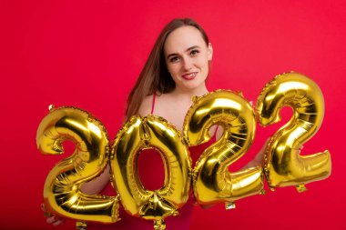 Yaklaşan tatiller - pembe elbiseli, gülümseyen bir esmer, kırmızı arka planda 2022 rakamlarını barındırıyor.