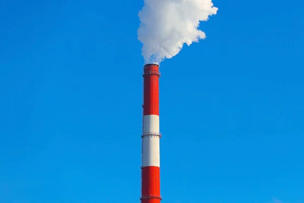 煙は青い空に対して赤い煙突から来ている — ストック写真
