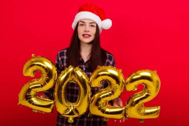 Noel, mutlu bayram kavramı - pijamalı genç bir kadın ve Noel Baba şapkası 2022 rakamlarını barındırıyor.