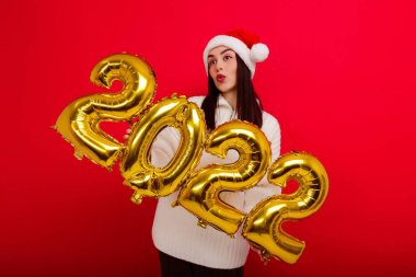Mutlu tatiller. Kırmızı Noel şapkalı genç bir kadın 2022 rakamlarını taşıyor.