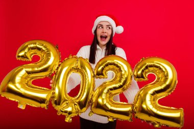 Mutlu tatiller. Kırmızı Noel şapkalı genç bir kadın 2022 rakamlarını taşıyor.