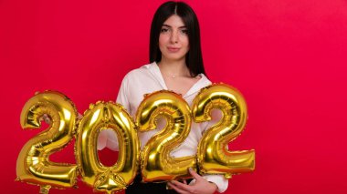 Yaklaşan tatillerde, beyaz gömlekli genç bir kadın 2022 rakamlarını taşıyor.