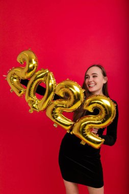 Tatiller, yeni yıl arifesi - siyah elbiseli genç bir kadın 2022 rakamlarını taşıyor.