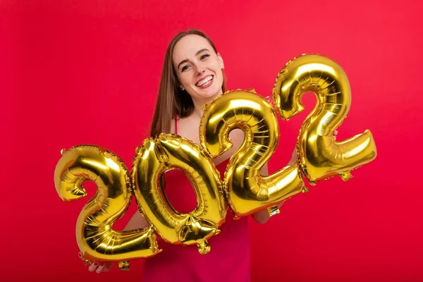 Yaklaşan tatiller - pembe elbiseli, gülümseyen bir esmer, kırmızı arka planda 2022 rakamlarını barındırıyor.