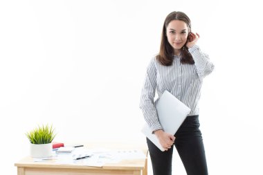 The brunette is standing next to the desk in a great mood
