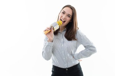 Gülümseyen esmer beyaz bir arka planda mikrofona şarkı söylüyor.