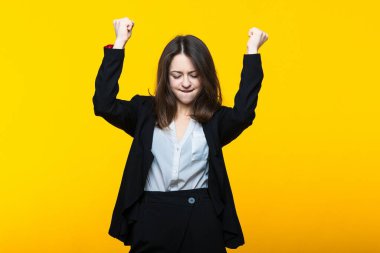 Sarı arka planda takım elbiseli mutlu genç bir kadın.