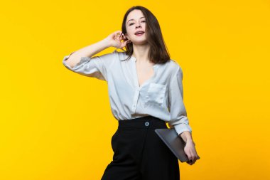 İş ve finans. Sarı arka planda dizüstü bilgisayarı olan genç ve güzel bir kadın.