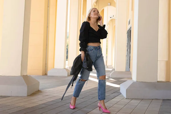 Uma Jovem Mulher Camisa Jeans Está Falando Telefone Enquanto Caminha — Fotografia de Stock