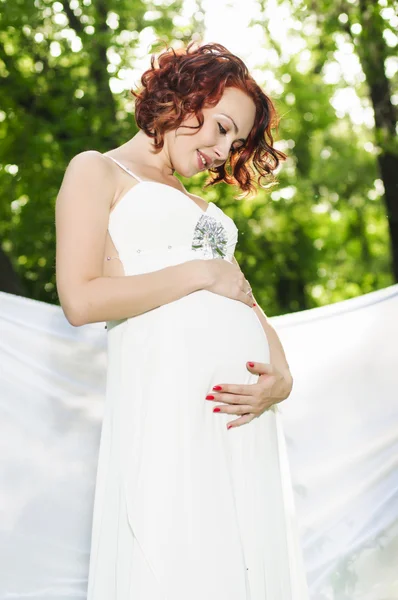 Jonge zwangere vrouw in witte jurk — Stockfoto