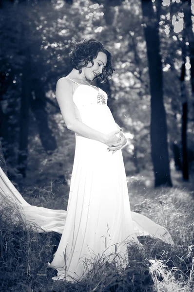 Młoda kobieta w ciąży w białej sukni — Zdjęcie stockowe