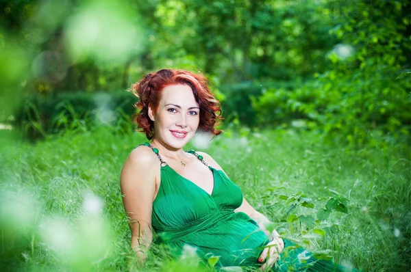 Νεαρή έγκυο γυναίκα σε ένα πράσινο φόρεμα — Φωτογραφία Αρχείου