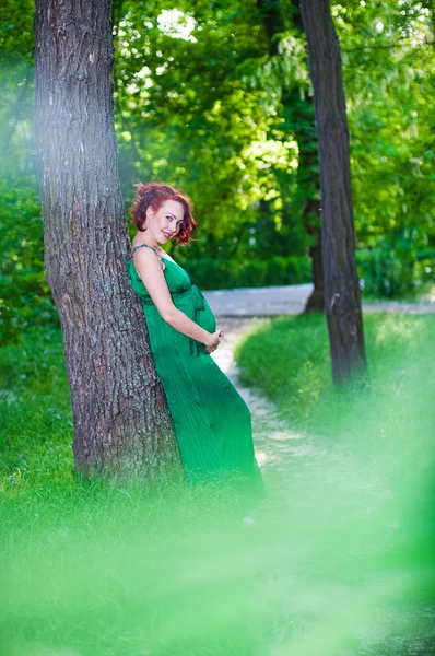 Молодая беременная женщина в зеленом платье — стоковое фото
