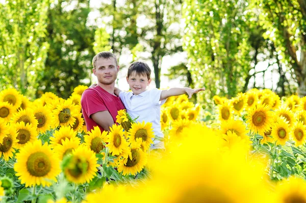 Far og gutt på en solsikkeåker – stockfoto