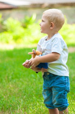 Bir oyuncakla parkta yürüyen çocuk